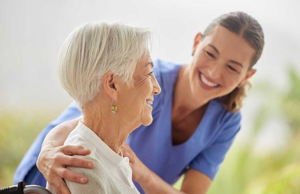 An older adult talking to a family member at a dining table with Medicare paperwork and a cup of tea.