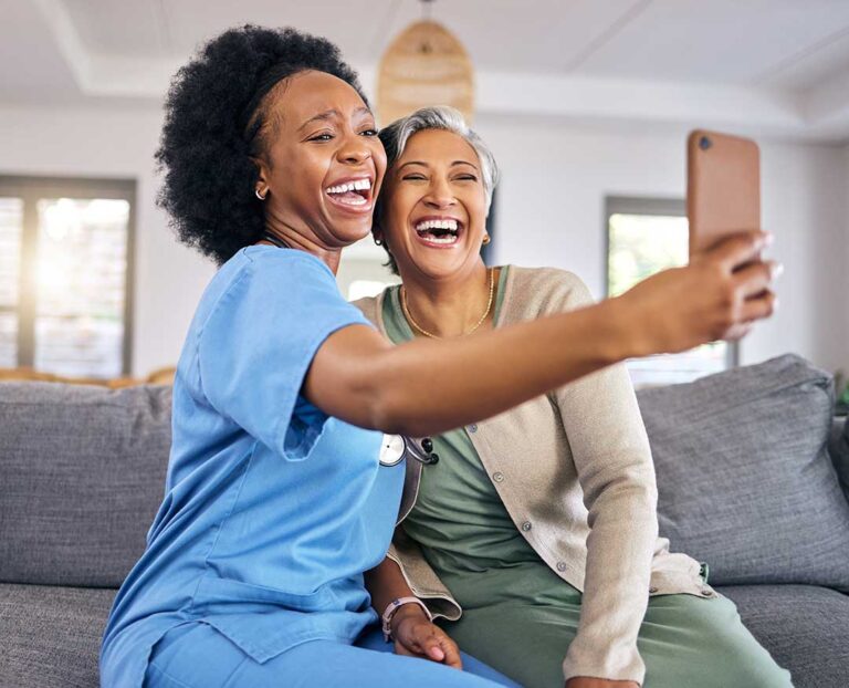 Older adults sitting together in a cozy living room, helping each other unpack belongings and chat companionably.